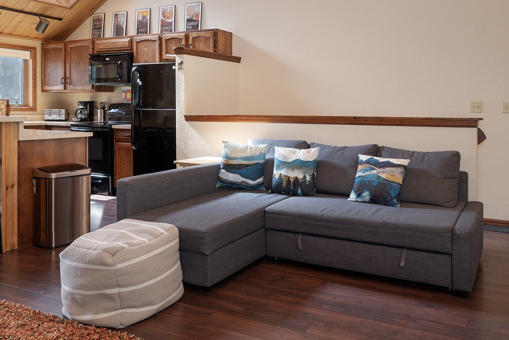 Relax in your cozy living space with mountain-themed pillows and natural wood details that create the perfect home away from home.