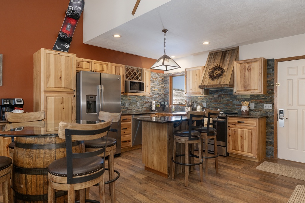 Gather around this stunning rustic kitchen at Mountainside B-20 featuring warm wood cabinets, stone backsplash, and modern appliances perfect for creating memorable meals together.