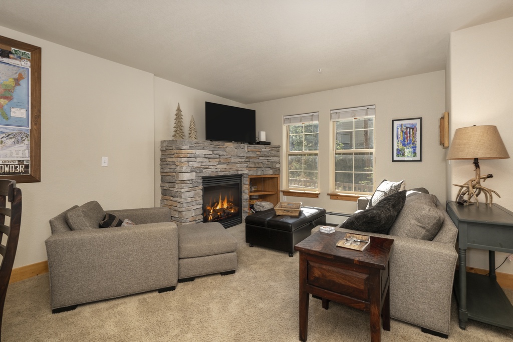 Settle into your cozy living space featuring a warm stone fireplace and comfortable seating—perfect for relaxing after a day of mountain adventures.