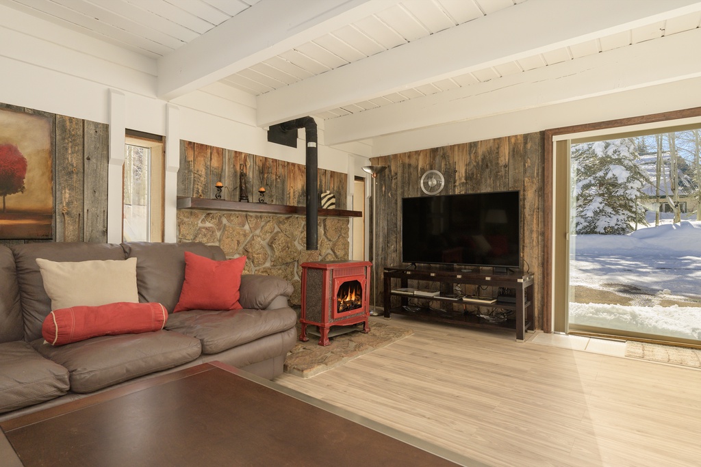 Cozy up by your crackling fireplace while enjoying mountain views through floor-to-ceiling windows in this rustic-chic living room.