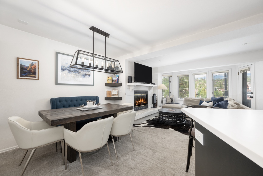 Unwind in your open-concept living space with cozy fireplace, modern dining area, and stylish furnishings perfect for memorable evenings together.