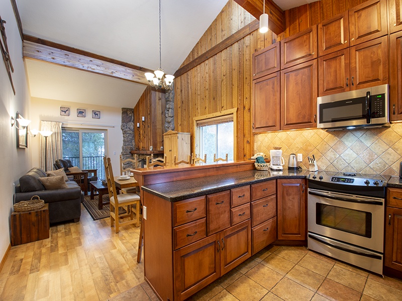 Your fully equipped kitchen features warm wood cabinetry and modern appliances, perfect for preparing meals while staying connected to the cozy living area.
