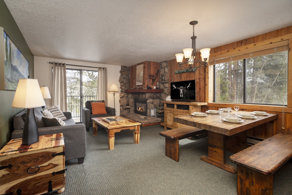Cozy up in your rustic mountain retreat with a stone fireplace, rustic dining nook, and forest views through expansive windows.