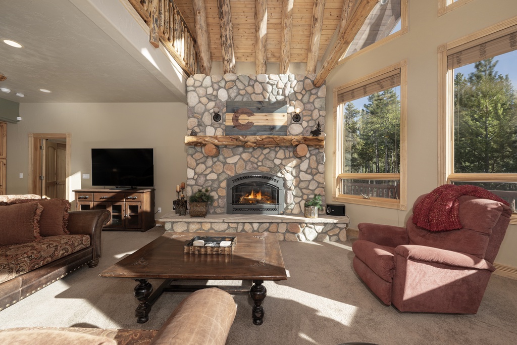 Unwind by your crackling stone fireplace while sunlight streams through tall windows, creating the perfect cozy mountain retreat atmosphere.