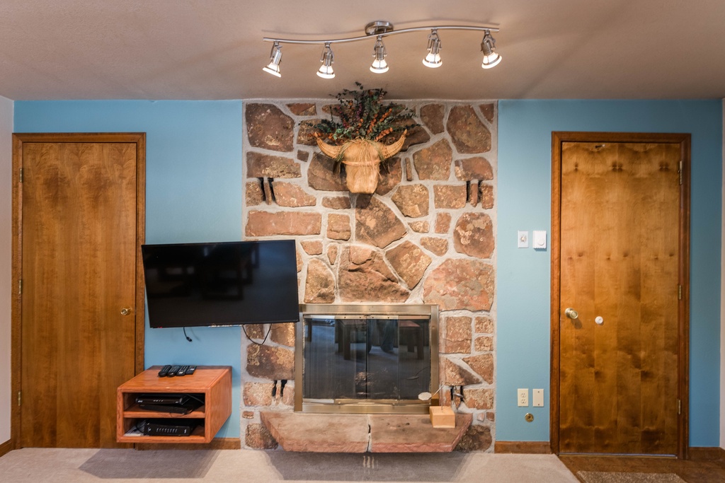Cozy up by the beautiful stone fireplace while your favorite shows play on the flat-screen TV in this welcoming living space.