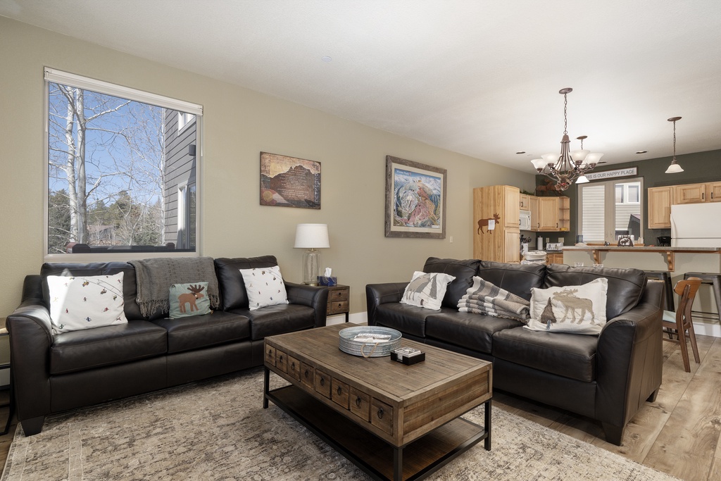Sink into plush leather sofas in your spacious living room, where natural light streams through large windows and rustic charm meets modern comfort.