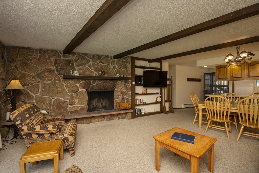 Cozy up in your rustic retreat with exposed beams, stone fireplace, and open dining space perfect for family gatherings.