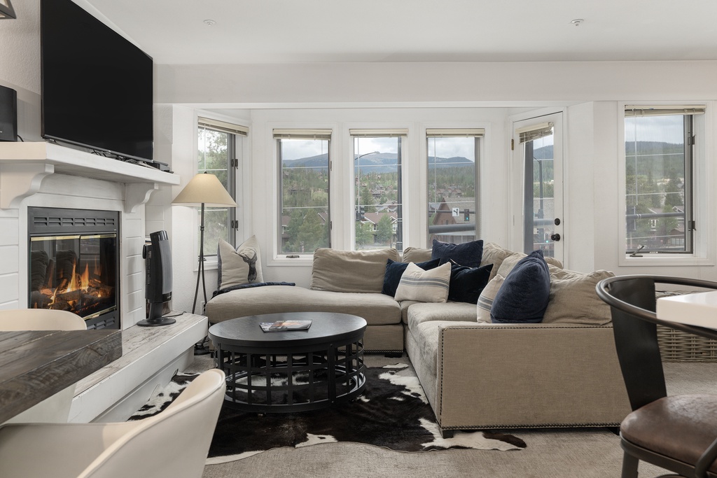 Sink into plush sectional seating by your crackling fireplace while mountain views frame your perfect retreat through panoramic windows.