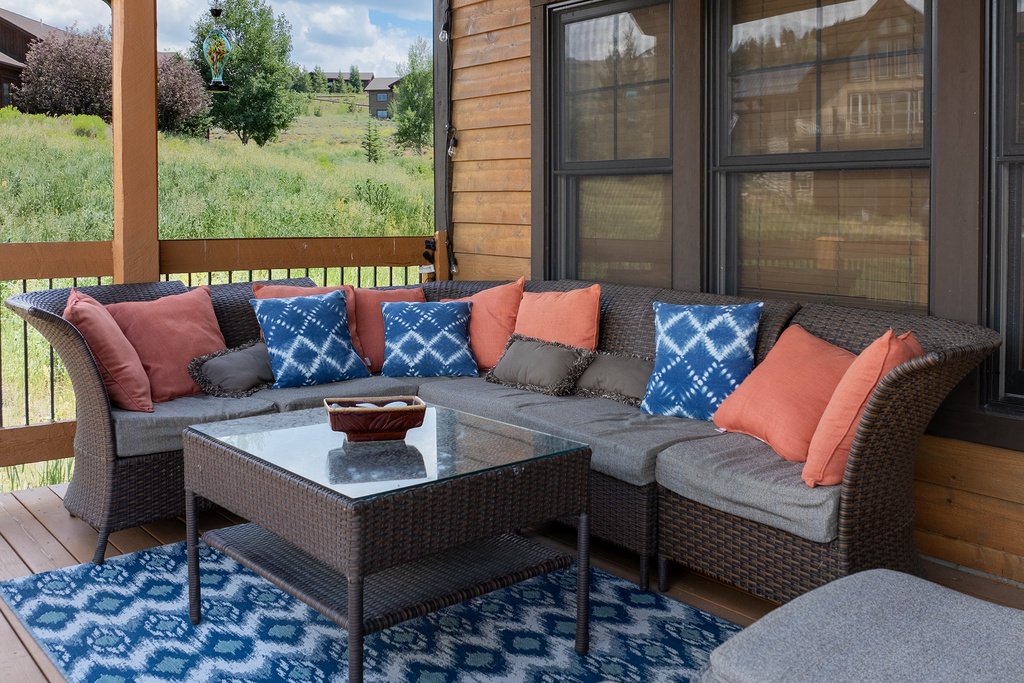 Sink into plush outdoor seating with vibrant pillows on your private deck, where morning coffee meets mountain meadow views.