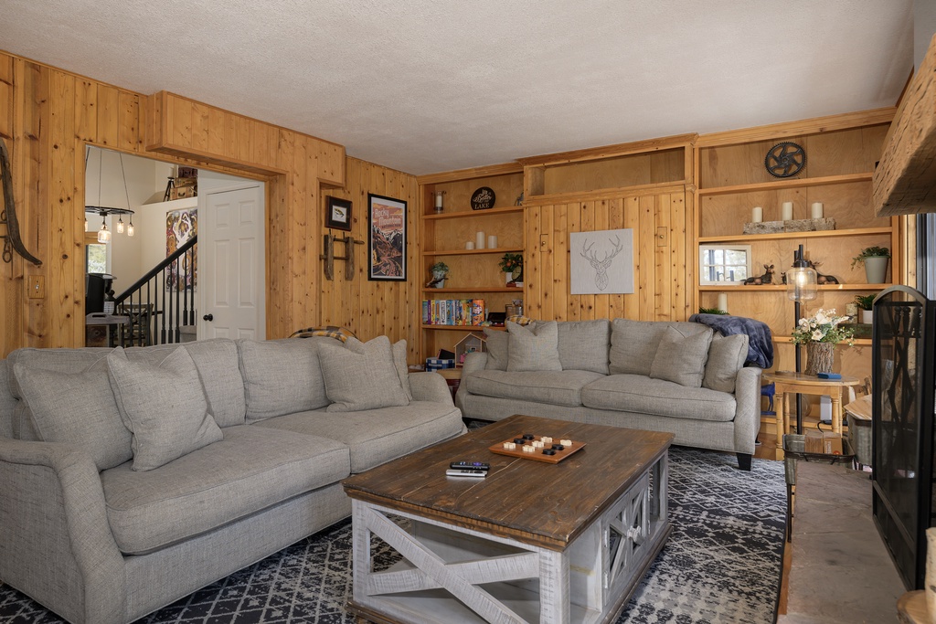Relax in your cozy living room at 1126 Western Road with warm wood paneling, plush gray sofas, and rustic charm that makes you feel right at home.