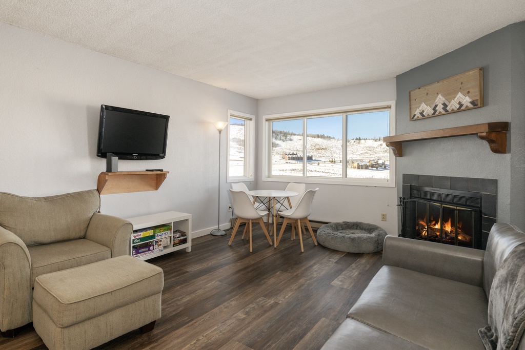 Cozy up by your crackling fireplace while gazing at snowy mountain views through large windows in this inviting living space.