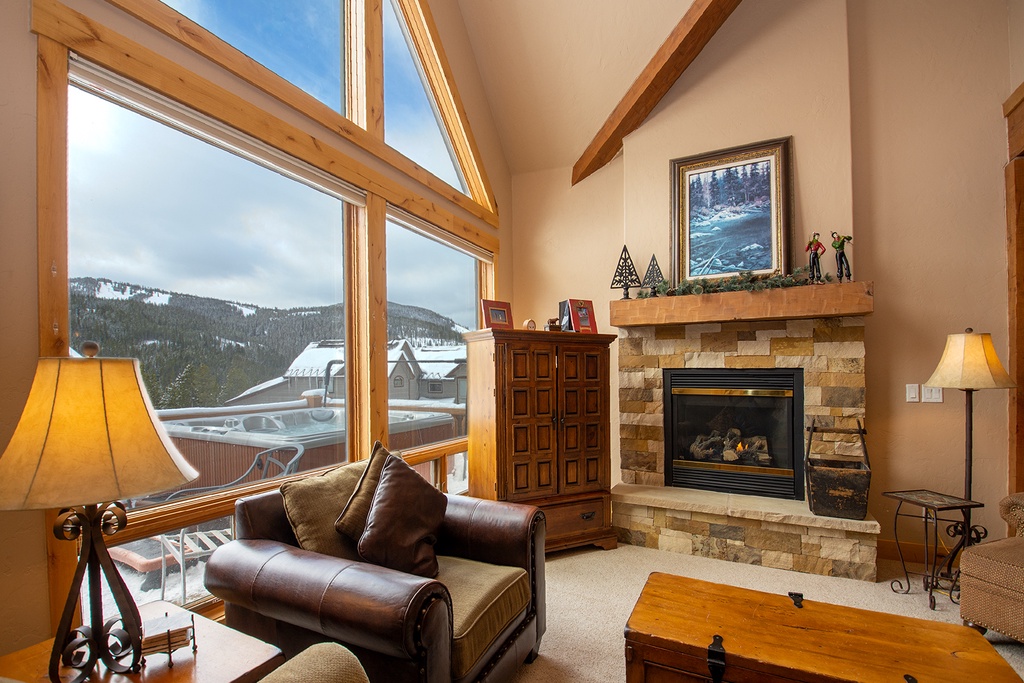 Cozy up by your crackling fireplace while enjoying mountain views through floor-to-ceiling windows in this warm living room.