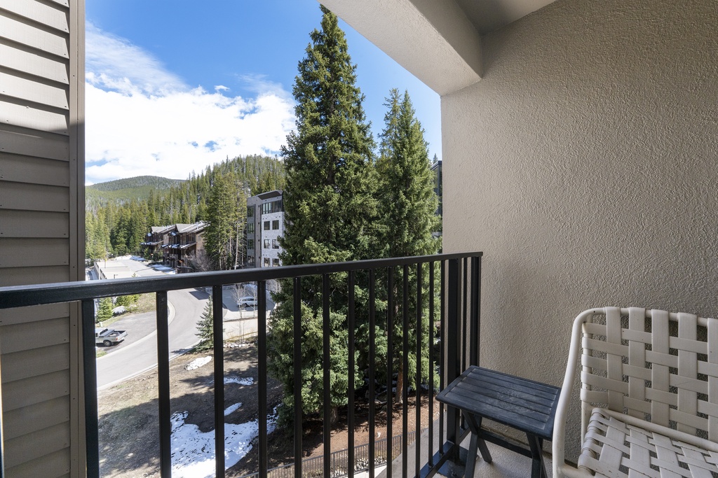 Step onto your private balcony and breathe in the crisp mountain air as you take in views of towering pines, nearby buildings, and tree-lined streets below.