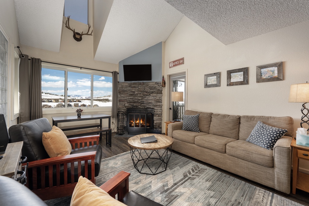Cozy up by your stone fireplace while enjoying mountain vistas through expansive windows in this welcoming living space.
