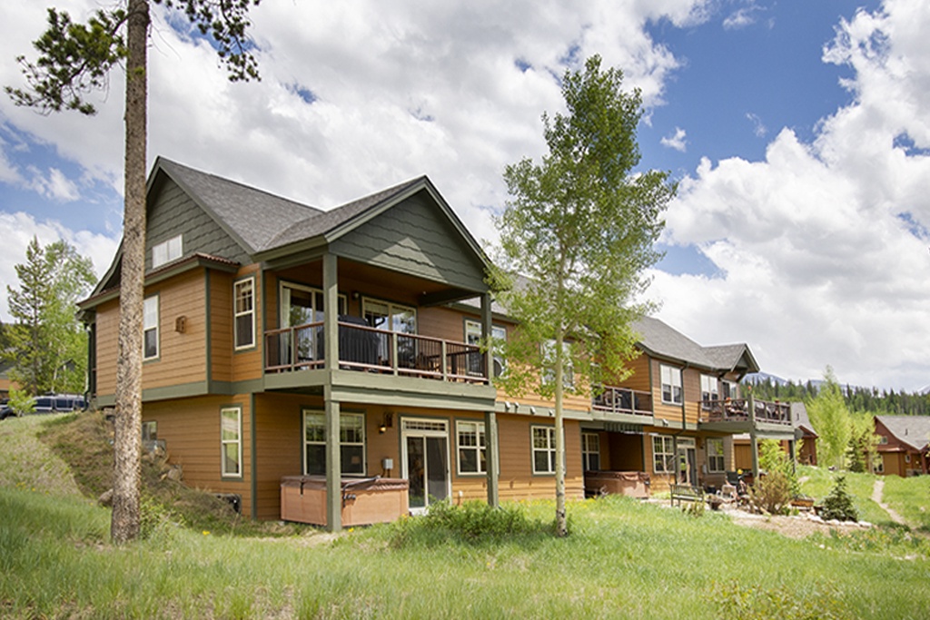 Charming mountain lodge with covered balcony surrounded by forest and meadow in peaceful natural setting.