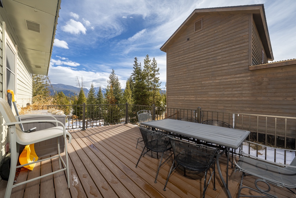 Expansive deck at 874 Kinnikinnick Road has outdoor dining and breathtaking mountain views surrounded by evergreen forest.