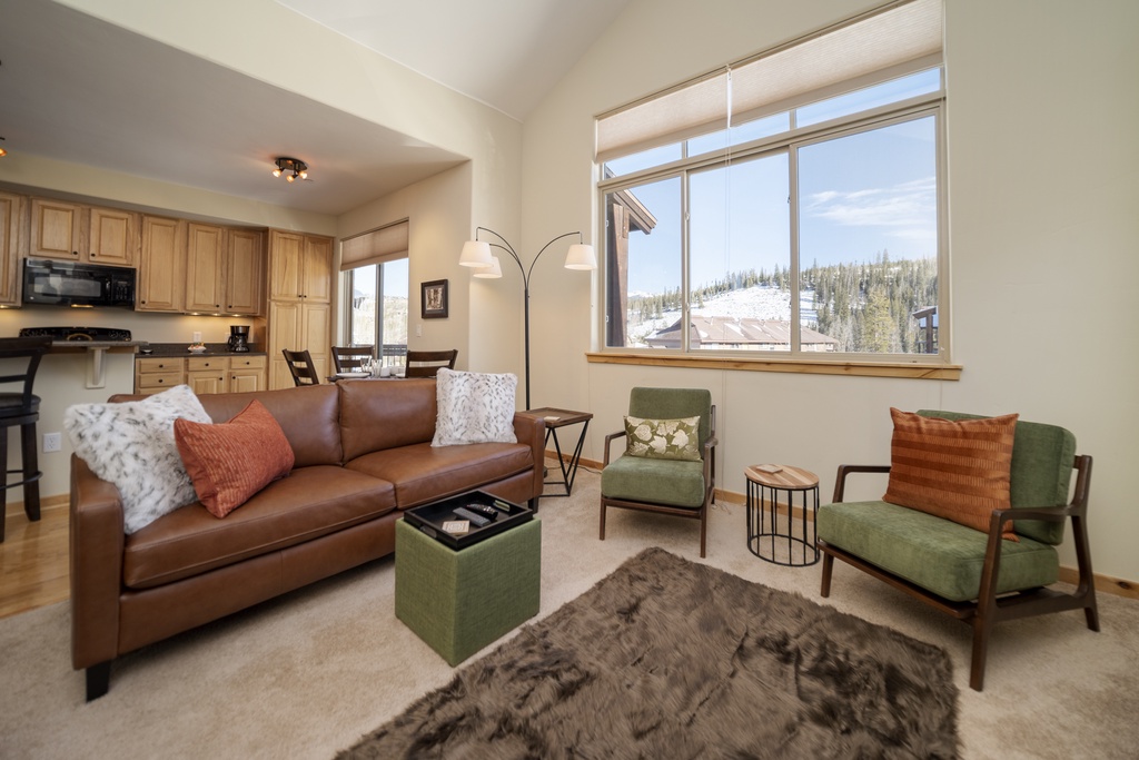 Relax in your cozy living room with plush leather seating and stunning mountain views through expansive windows.