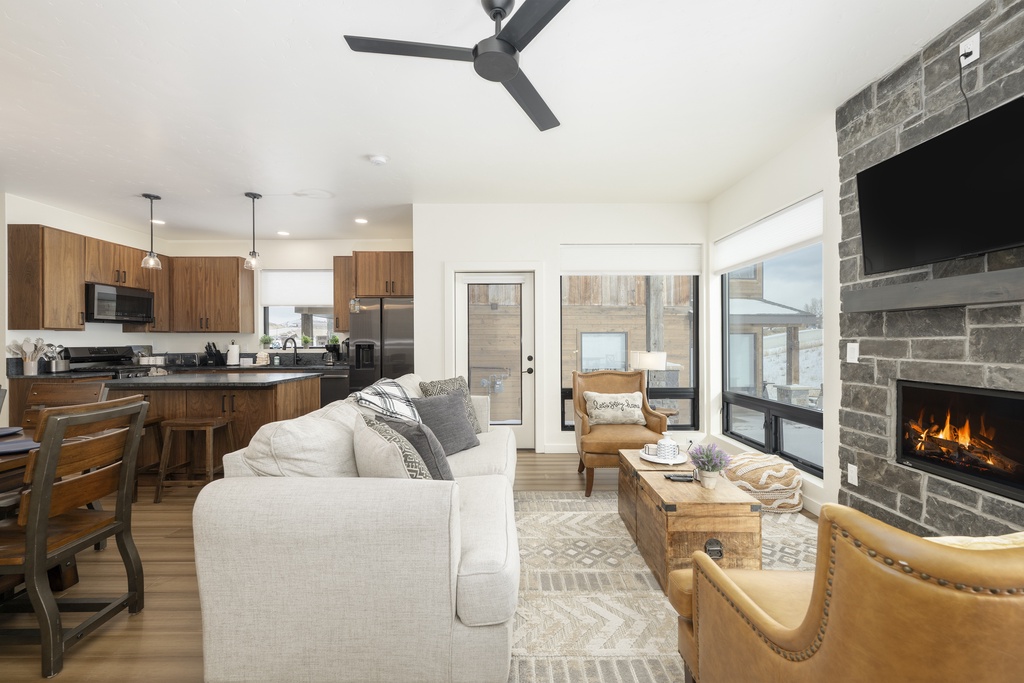 Relax in your open-concept haven where modern kitchen flows into cozy living space, complete with crackling fireplace and warm wood accents.