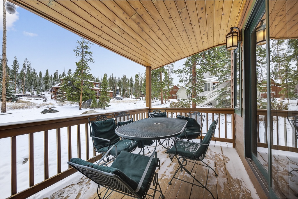 Cozy covered balcony with dining seating overlooking snowy winter forest views—your perfect mountain retreat spot at 21 GCR 4435.