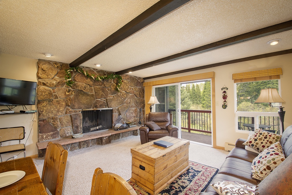 Cozy up beside the stone fireplace while watching nature through sliding glass doors that open to your private deck.