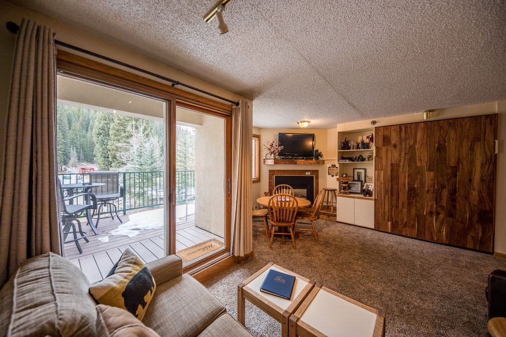 Relax in your cozy mountain retreat with warm wood accents, fireplace, and private balcony overlooking forest views.