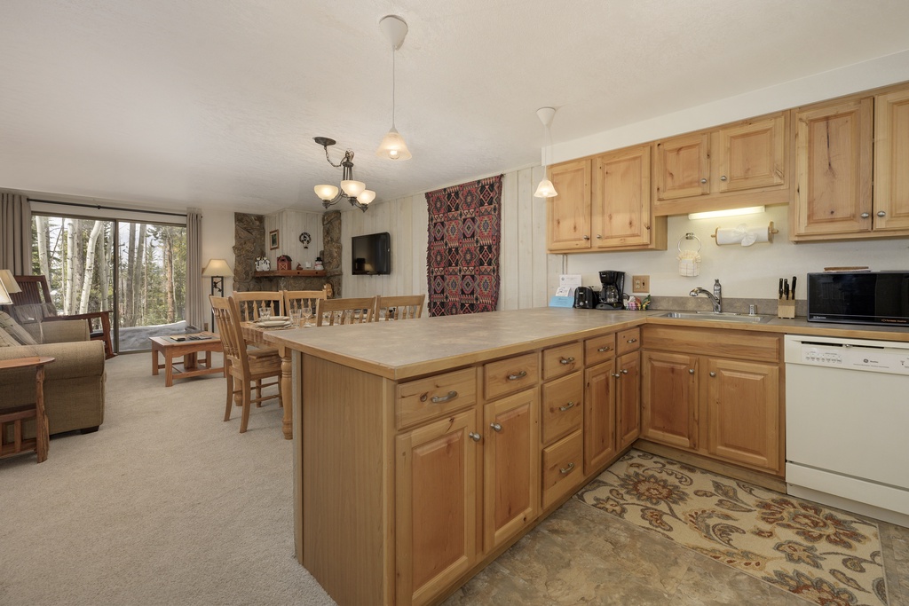 Your spacious kitchen features warm wood cabinets and flows into the cozy living area with peaceful forest views.