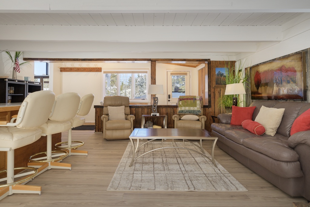 Sink into plush leather seating surrounded by warm wood beams and natural light streaming through expansive windows overlooking snow-dusted trees.