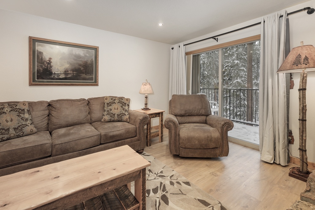 Unwind in your cozy living room with plush seating and stunning winter views through the balcony doors.