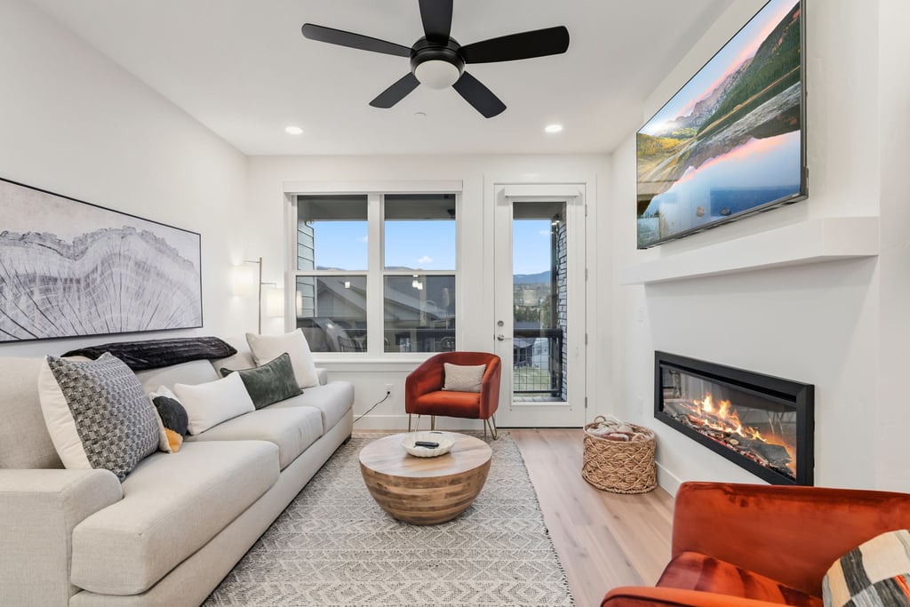 Unwind in your stylish living space with crackling fireplace, plush seating, and natural light streaming through floor-to-ceiling windows.