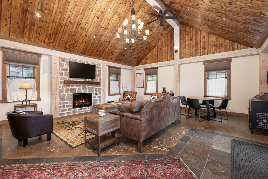 Gather around your cozy stone fireplace in this stunning vaulted-ceiling living space, where rustic wood beams and leather seating create the perfect retreat.