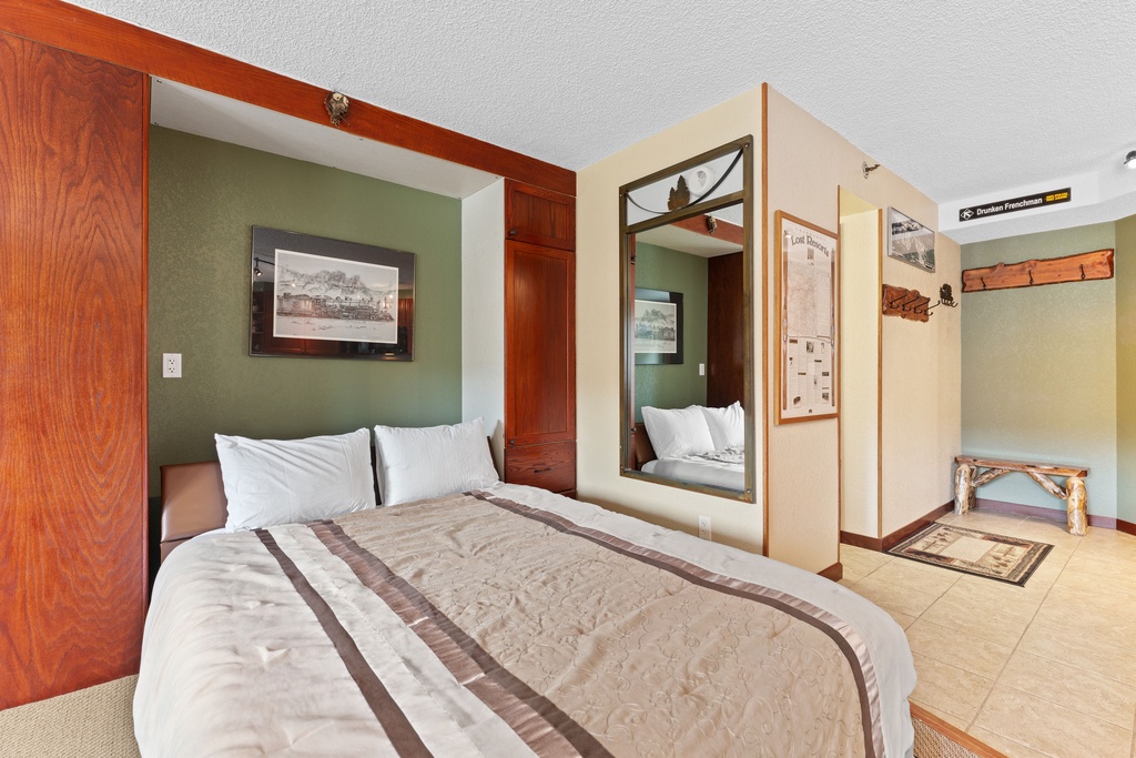 Unwind in your cozy retreat with a plush bed, charming rustic accents, and a welcoming entryway that invites relaxation after a day of adventure.