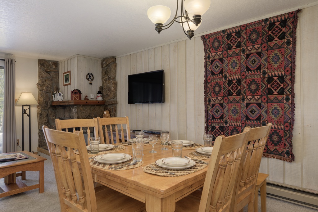 Gather around your rustic dining table for memorable meals, with charming stone fireplace and warm décor creating the perfect mountain retreat atmosphere.