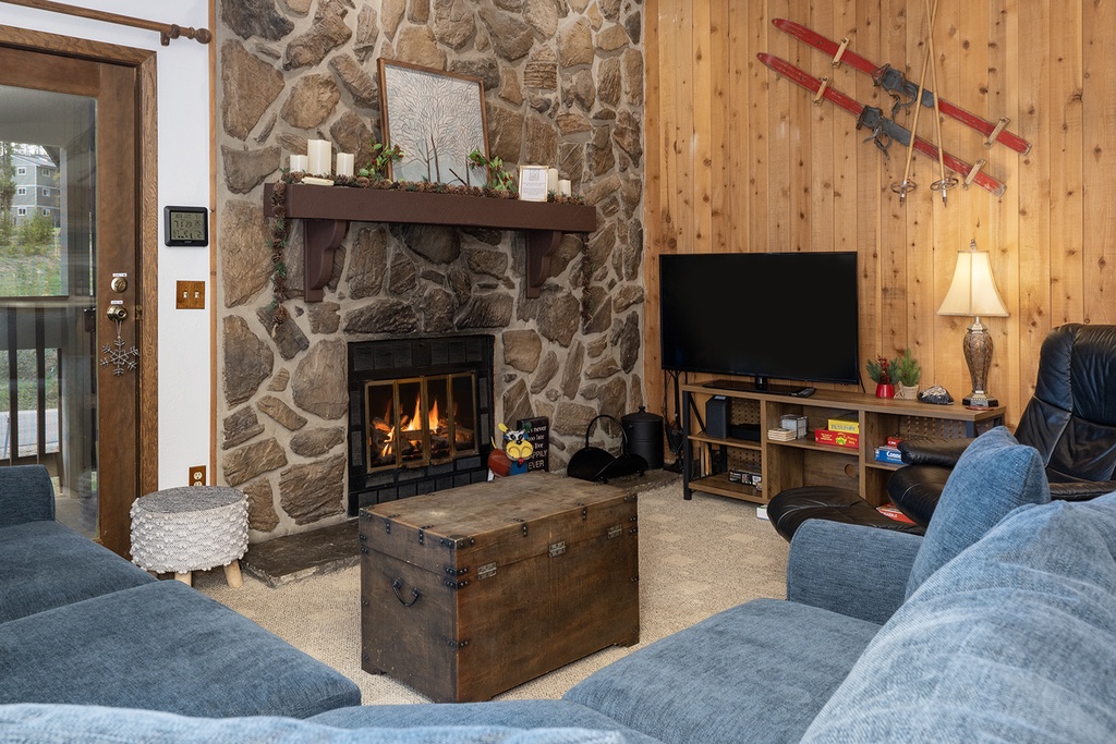 Cozy up by your crackling stone fireplace while watching TV on plush blue sofas in this warm mountain retreat.