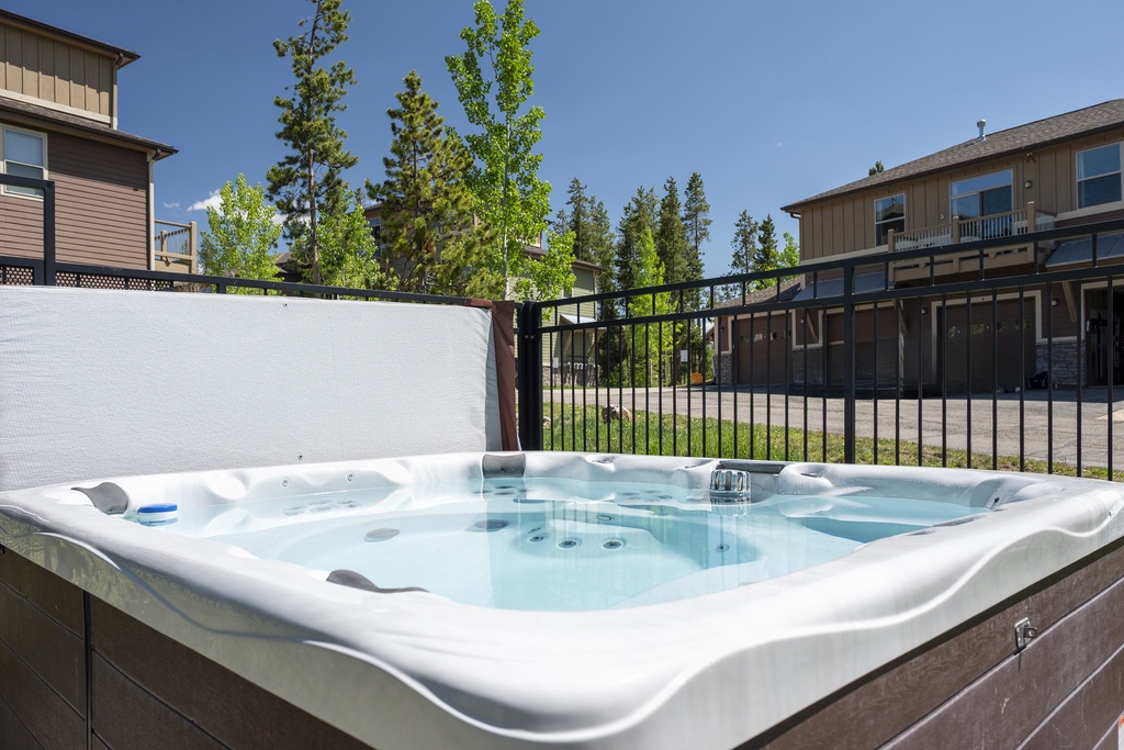 Soak in the common area hot tub under blue skies, surrounded by mature trees and tranquil residential views.