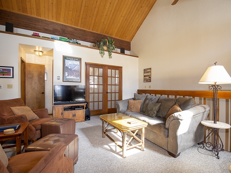Unwind in your spacious living room featuring vaulted wood ceilings, plush gray sofa, and rustic charm with modern comfort for relaxing evenings.
