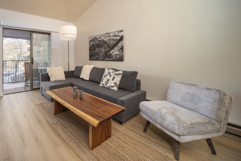 Your bright living space features modern comfort with a cozy sectional, warm wood accents, and peaceful mountain artwork.