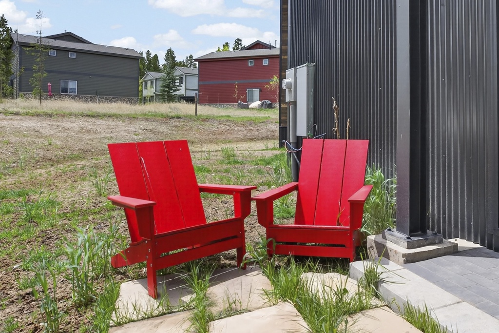 A modern vacation property located in a peaceful residential setting, offering a quiet retreat with contemporary dark exterior architecture and vibrant outdoor seating near the entrance.