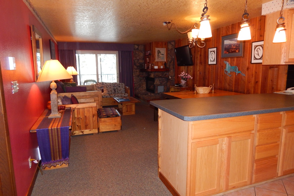 Cozy mountain retreat with warm wood touches, stone fireplace, and open kitchen - your perfect ski lodge escape awaits.