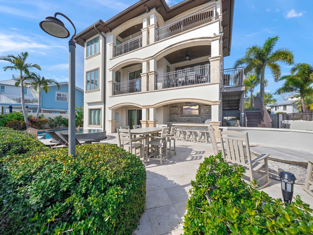 Modern three-story vacation rental with tropical landscaping and outdoor dining area