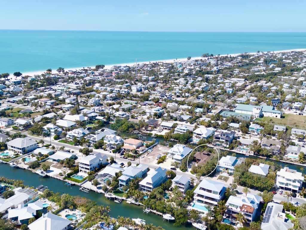 Aerial view of a coastal neighborhood with waterfront homes, canals, and beach access in a picturesque seaside community.