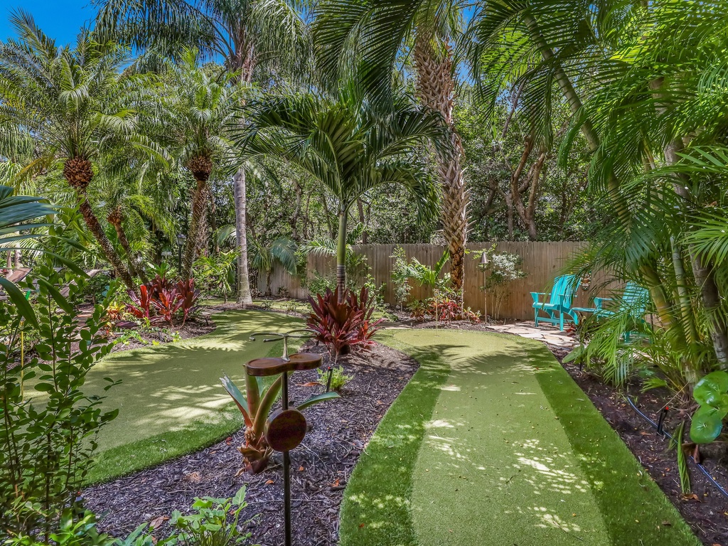 Tropical paradise awaits in your private backyard with lush palms, putting green, and colorful seating under endless blue skies.