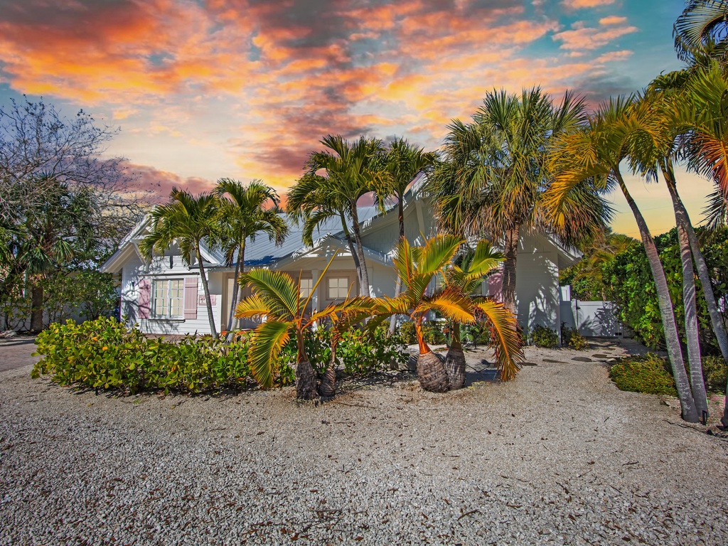 Home exterior with tropical landscaping beneath sunset sky