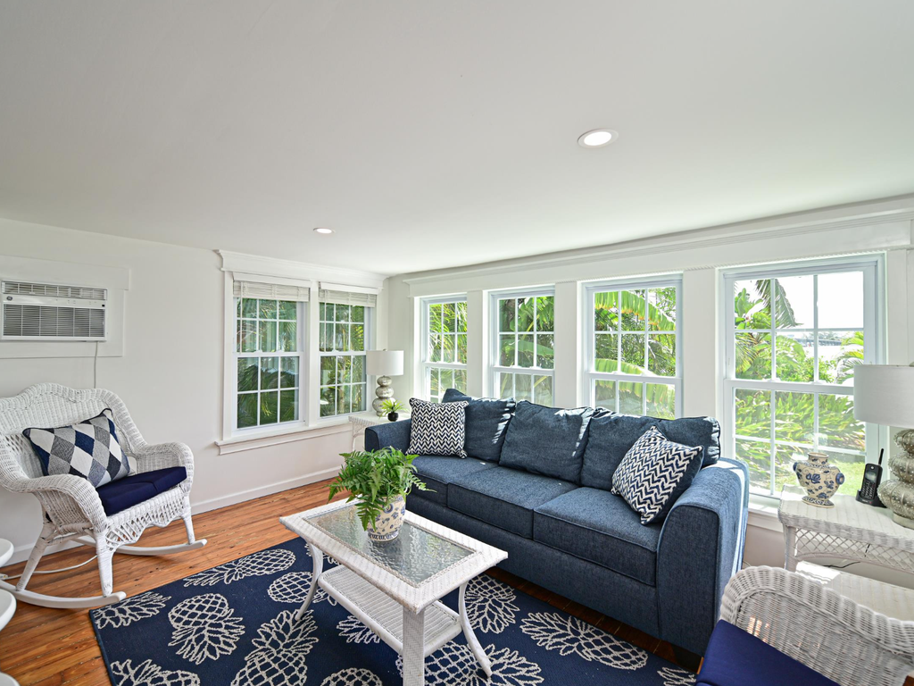 Relax in your bright, airy living room with comfortable seating and large windows framing lush tropical views.