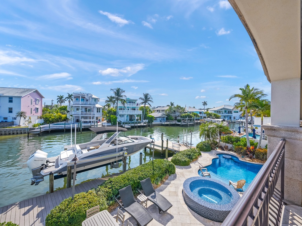 Waterfront view showcasing private dock with boat access, and poolside relaxation area