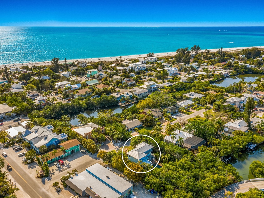 Aerial view of a coastal neighborhood with beautiful turquoise waters and pristine beach nearby.