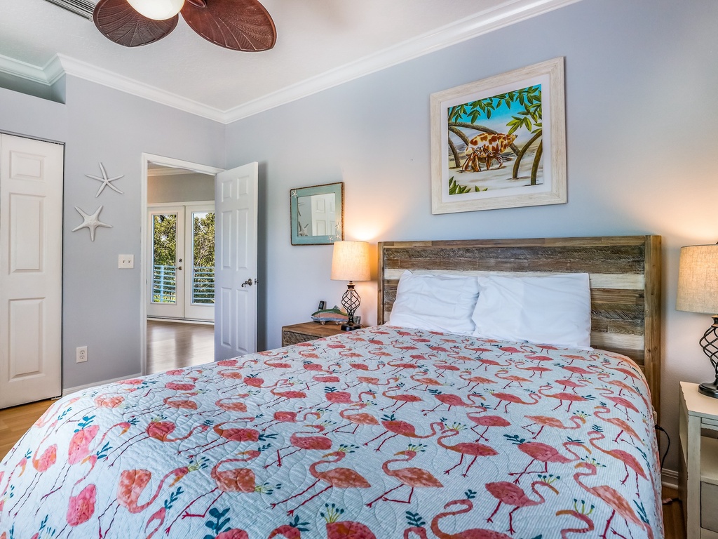 Unwind in your coastal bedroom with tropical flamingo bedding, rustic wood headboard, and soothing blue walls that create the perfect beach getaway atmosphere.