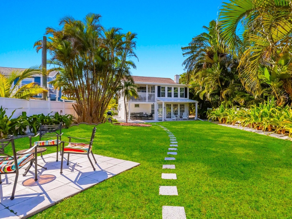 Step into your private tropical paradise with lush green lawn, swaying palms, and a charming pathway leading to your elegant retreat.