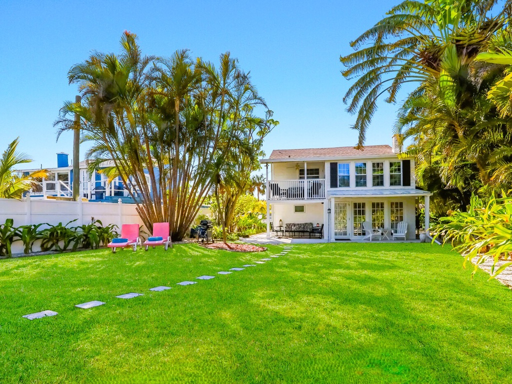 Tropical paradise with expansive lawn surrounded by swaying palms and colorful flowers. Private outdoor sanctuary perfect for relaxation.