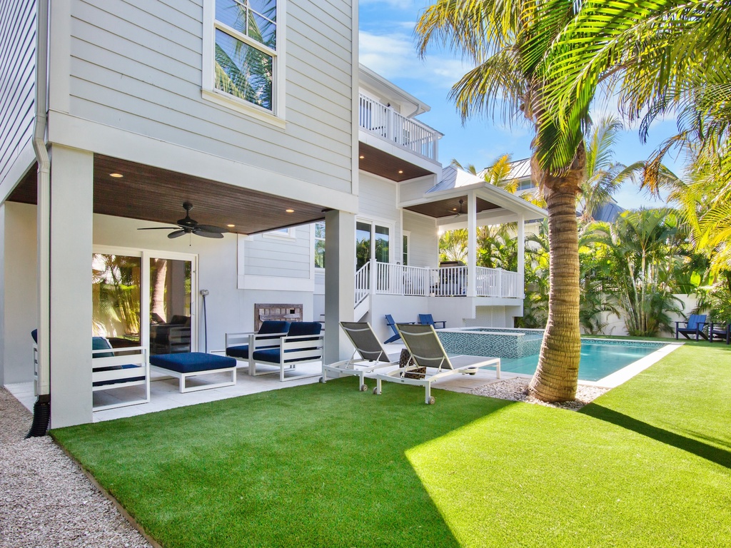 Sparkling pool, lush palm trees, and covered lounge area perfect for outdoor relaxation.