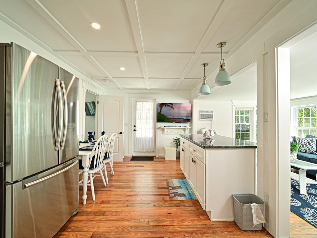 Your spacious kitchen features gleaming hardwood floors, modern stainless appliances, and bright coastal charm perfect for preparing memorable meals together.